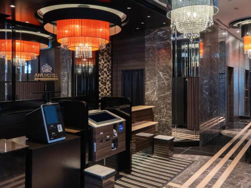 a lobby of a hotel with a cash register and chandeliers at APA Hotel Higashi Shinjuku Kabukicho Higashi in Tokyo