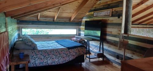 a bedroom with a bed in a wooden cabin at Hostal Arboretum cafeteria & jardin in Hijuelas