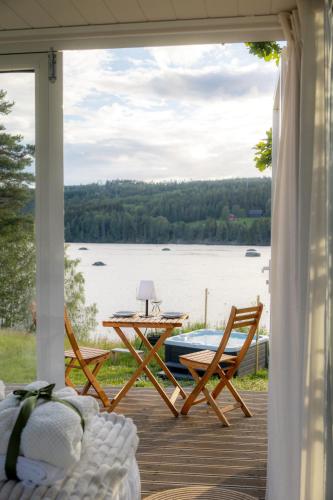 a porch with a table and chairs and a view of a lake at Gnist Retreat in Sørumsand