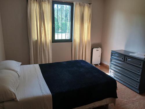 ein Schlafzimmer mit einem Bett, einer Kommode und einem Fenster in der Unterkunft La isabela in Mar del Plata