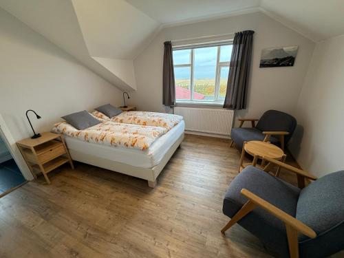 a bedroom with a bed and two chairs and a window at Sudur-Bár Guesthouse in Grundarfjordur