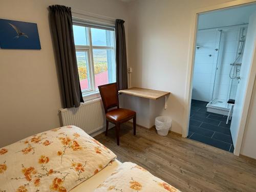 a bedroom with a bed and a chair and a window at Sudur-Bár Guesthouse in Grundarfjordur