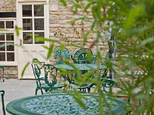 an outdoor table and chairs with a stone building at The Blenheim Buttery in Woodstock