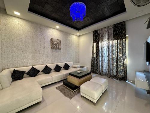 a living room with a large white couch and stool at Joyous stay in Jaipur
