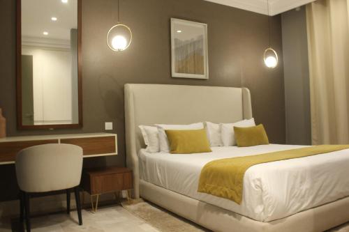 a bedroom with a bed and a table and a chair at M Résidence Marrakech Luxury Serviced Apartments in Marrakesh