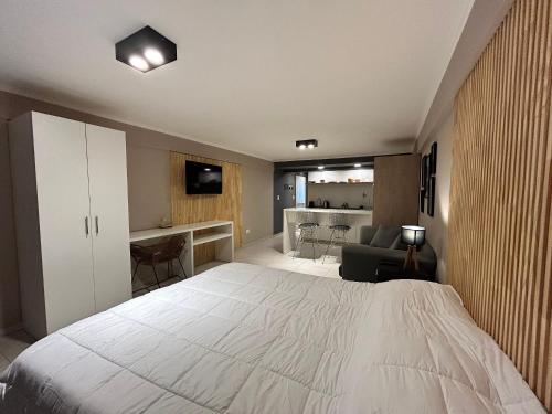 a bedroom with a large white bed and a living room at 4 Estaciones in El Bolsón