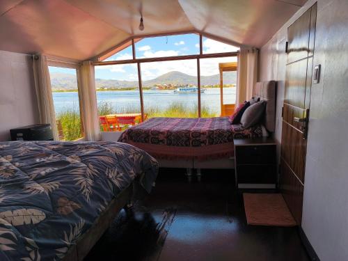 a room with two beds and a large window at Uros Quechua`s Lodge Titicaca in Puno