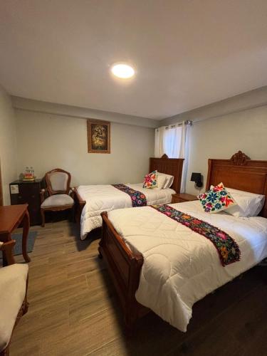 a hotel room with three beds and a chair at Rumi Wasi Inn Ollantaytambo in Ollantaytambo