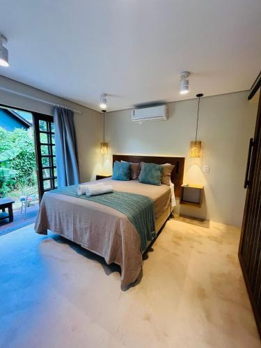 a bedroom with a large bed and a large window at Studio com Jacuzzi na Natureza Casal Baoba Suite in Bombinhas
