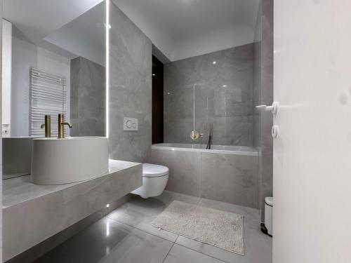 a bathroom with a tub and a sink and a toilet at Cortina - Yard & Wellness View in Voluntari