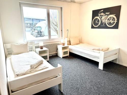 a bedroom with two beds and a window with a bike on the wall at Private 5 bedroom for large Groups in Hunzenschwil