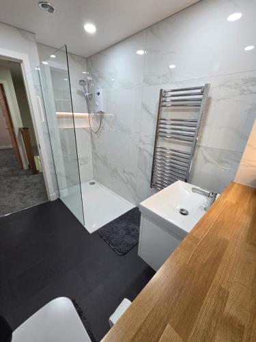 a white bathroom with a shower and a sink at 25 Colliers Road,Stirling in Plean Station