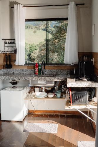 a kitchen with a counter with a sink and a window at Chalé Romântico em Itamonte-MG in Itamonte