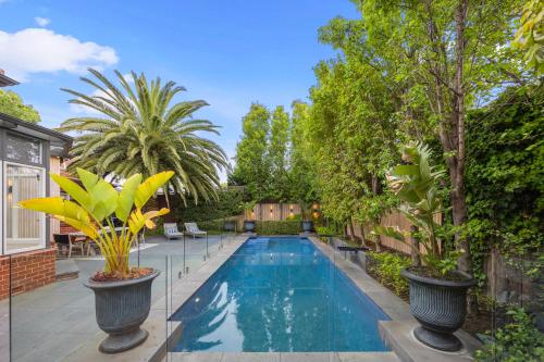 a swimming pool in a backyard with two large plants at Complete Host Brighton House in Melbourne