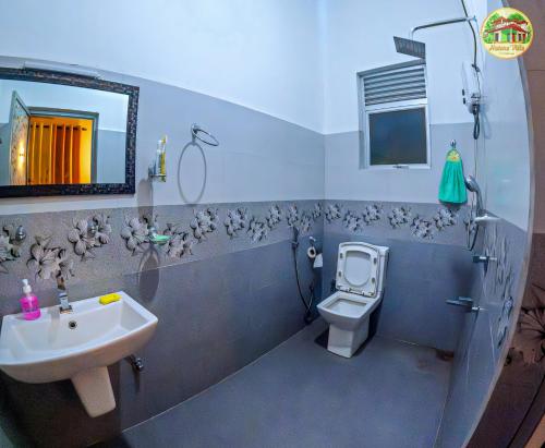 a bathroom with a sink and a toilet and a mirror at Natura Villa in Hiriketiya