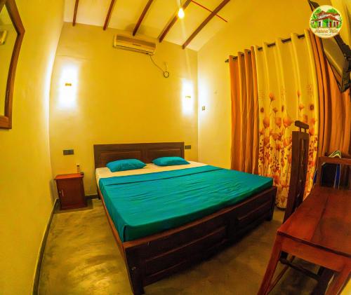 a bedroom with a bed with green sheets and a desk at Natura Villa in Hiriketiya