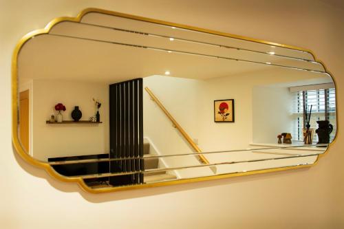 a mirror hanging on a wall with a staircase at Coorie-In Cottage in Whitehills