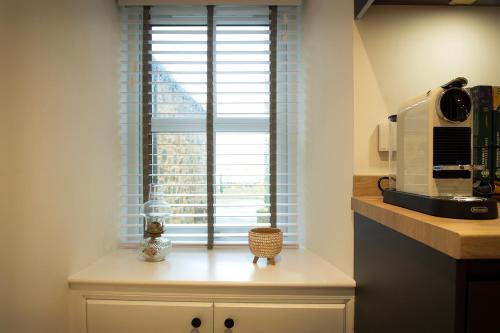 a kitchen counter with a window and a microwave at Coorie-In Cottage in Whitehills
