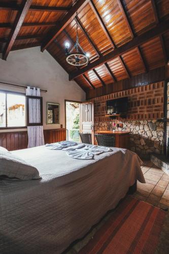 a bedroom with a large bed and a stone wall at Pousada Serras De Monte Verde in Monte Verde