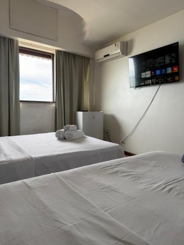 a hotel room with two beds and a television at Pasárgada frente ao mar in Vila Velha