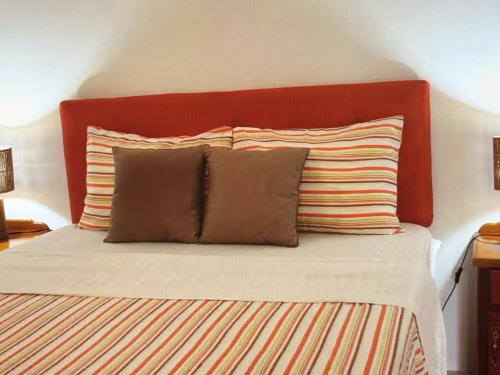 a bed with a red headboard and two pillows at Tropical Tabago in Carnbee Village