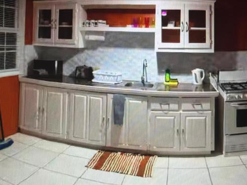 a kitchen with white cabinets and a sink at Tropical Tabago in Carnbee Village