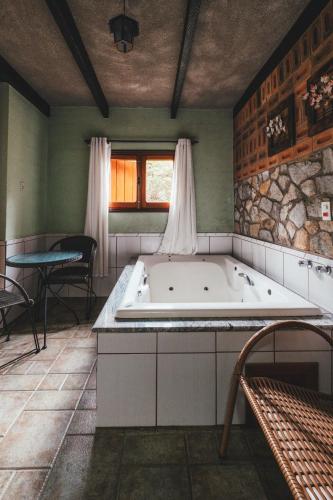 a large bath tub in a room with a table at Pousada Serras De Monte Verde in Monte Verde