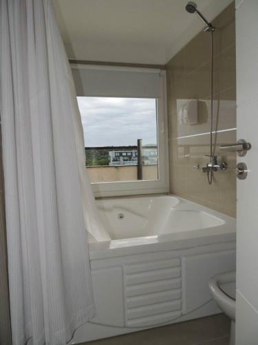 a white bathroom with a tub and a window at Linda Bay Playa in Mar de las Pampas