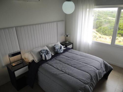a bedroom with a bed with pillows and a window at Linda Bay Playa in Mar de las Pampas