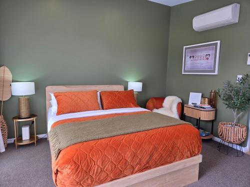 a bedroom with a large bed with orange pillows at “No.25”Stand alone guest studio unit in Twizel