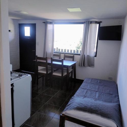 a small room with a table and a kitchen with a window at Departamento 8 in El Bolsón