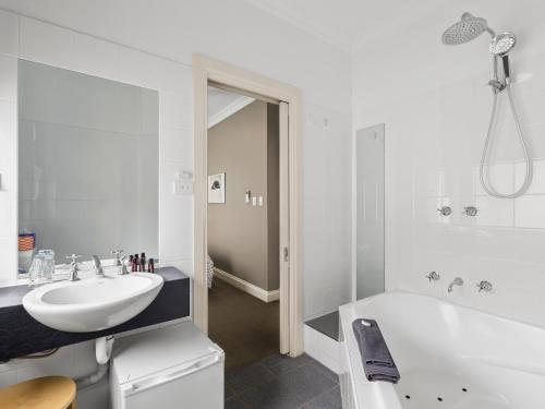 a white bathroom with a sink and a bath tub at Athelstane Hotel in Queenscliff