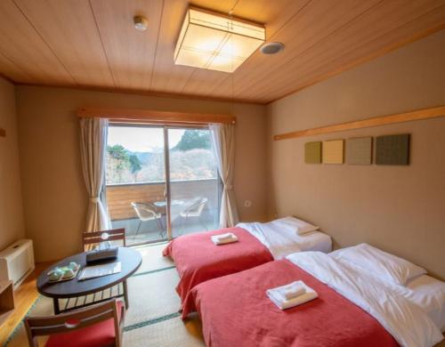 a bedroom with two beds and a table and a window at ザランタン鹿沼 in Kanuma