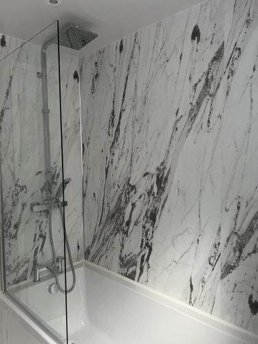 a bathroom with a shower and a white marble wall at New 2-bed 2-bath detached flat with garden in Enfield