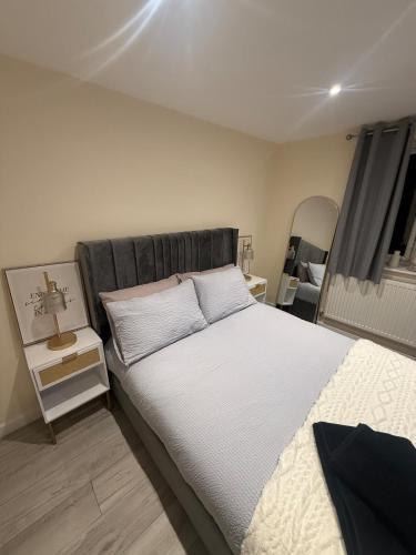 a bedroom with a large bed and a night stand at New 2-bed 2-bath detached flat with garden in Enfield