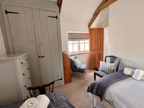 a bedroom with a bed and a chair and a window at 14 Boscaswell Downs in Lower Boscaswell