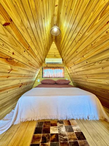 a bedroom with a bed in a wooden room at Chale do Boni in Palhoça
