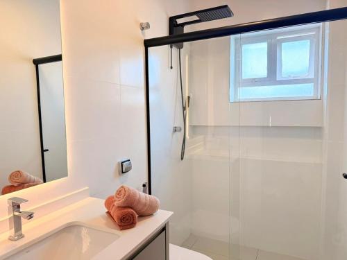 a bathroom with a glass shower and a sink at Apartamento Central em Araxá in Araxá