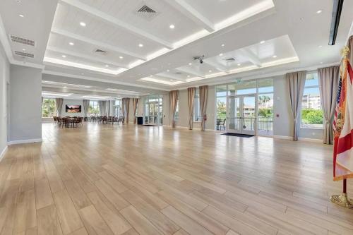 a large room with a hard wood floor and windows at Chic Ocean Getaway - Walk to Beach, Pool & Hot Tub in Fort Pierce