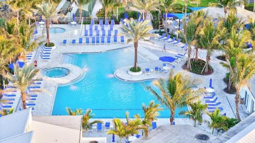 an aerial view of a resort pool with palm trees at Chic Ocean Getaway - Walk to Beach, Pool & Hot Tub in Fort Pierce