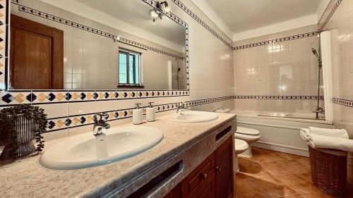 a bathroom with two sinks and a tub and a toilet at Coreto's Village in Praia Verde