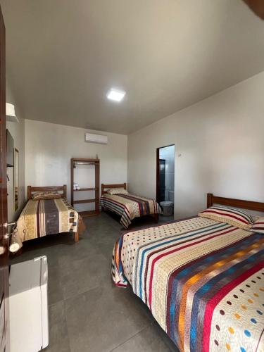 a hotel room with three beds and a mirror at Pousada Iza in Salinópolis