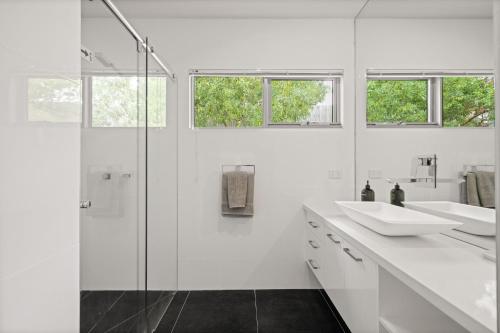 a white bathroom with two sinks and a shower at Cliff Top Retreat in San Remo