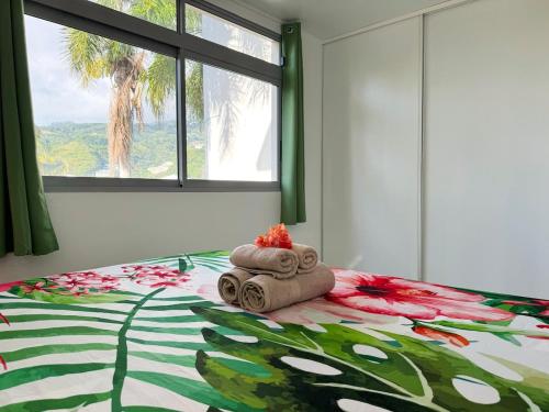 a bedroom with a bed with towels and a palm tree at Private beach access, fiber optic internet & parking in Punaauia
