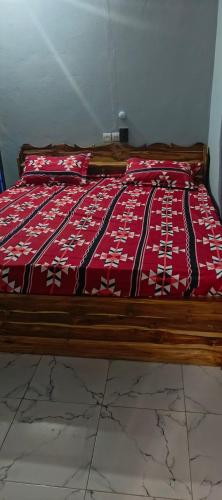 a bed with a red and white blanket on it at Tonton Love in Palimé