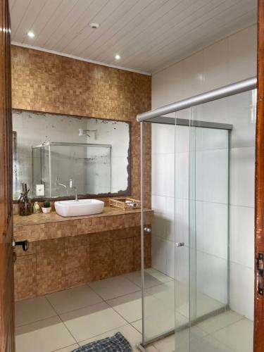 a bathroom with a glass shower and a sink at Casa ao ar livre in Aracaju