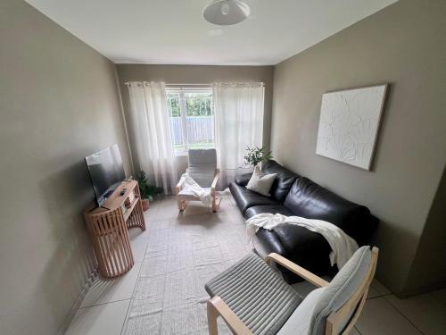 a living room with a black leather couch and a chair at u5-Traditional QLD unit with backyard-Fresh-Quiet Leafy Centre-NewAC SmartTV in Brisbane
