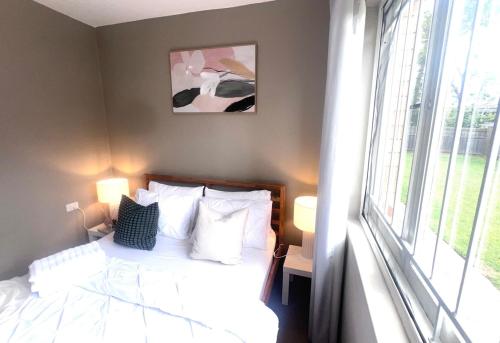 a bedroom with a bed with white pillows and a window at u5-Traditional QLD unit with backyard-Fresh-Quiet Leafy Centre-NewAC SmartTV in Brisbane