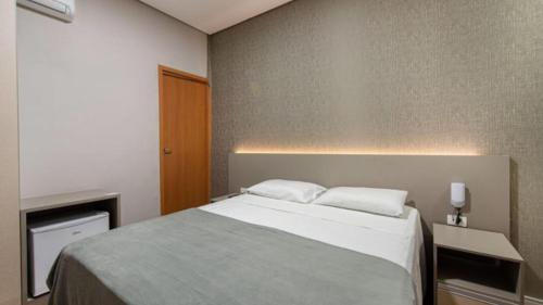a bedroom with a large bed with two pillows at Florida Limeira Hotel in Limeira