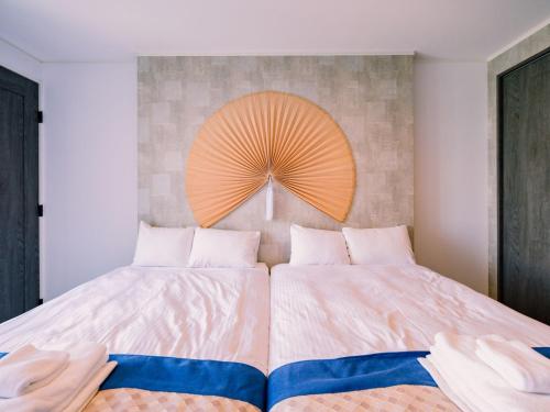 a bedroom with two beds and an orange fan on the wall at abundance okinawa & Kourijima Sauna resort in Kouri